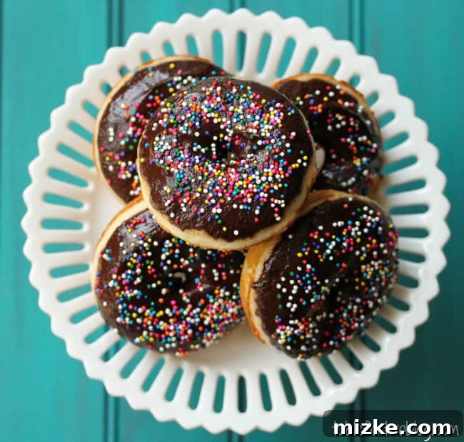 Irresistible Chocolate Sprinkle Donuts 3 A close-up of a hand dipping a donut into rich chocolate glaze.