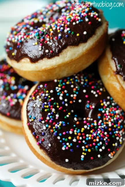 Irresistible Chocolate Sprinkle Donuts 4 Freshly baked chocolate donuts cooling on a wire rack before glazing.