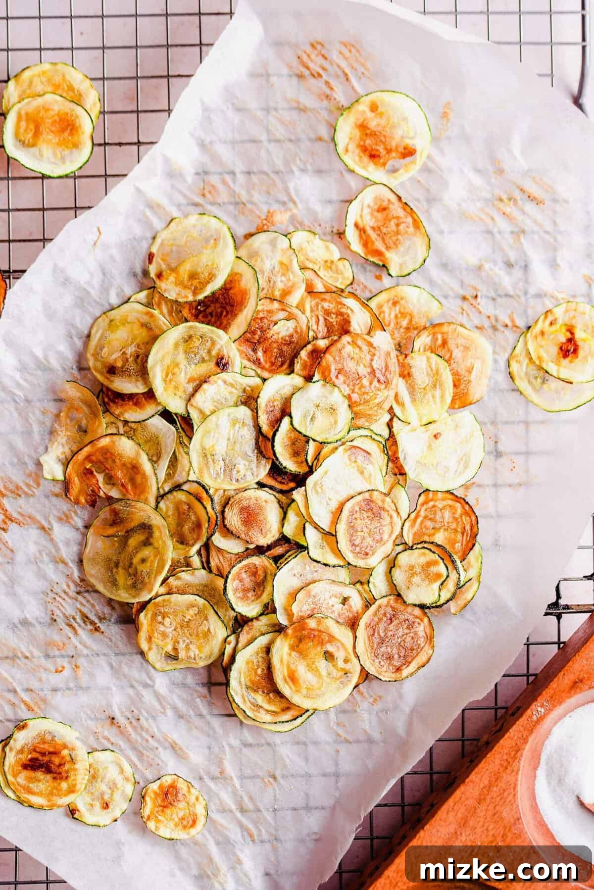 Simple Golden Zucchini Crisps 5 Overhead view of golden zucchini chips on parchment paper after baking