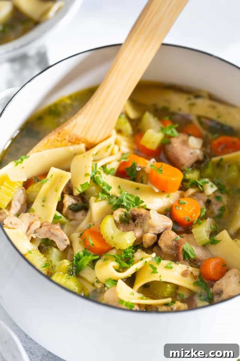 Simmering Perfection: Crafting Your Ultimate Homemade Chicken Noodle Soup A large pot of chicken noodle soup simmering on a stove, with a wooden spoon stirring the hearty ingredients.
