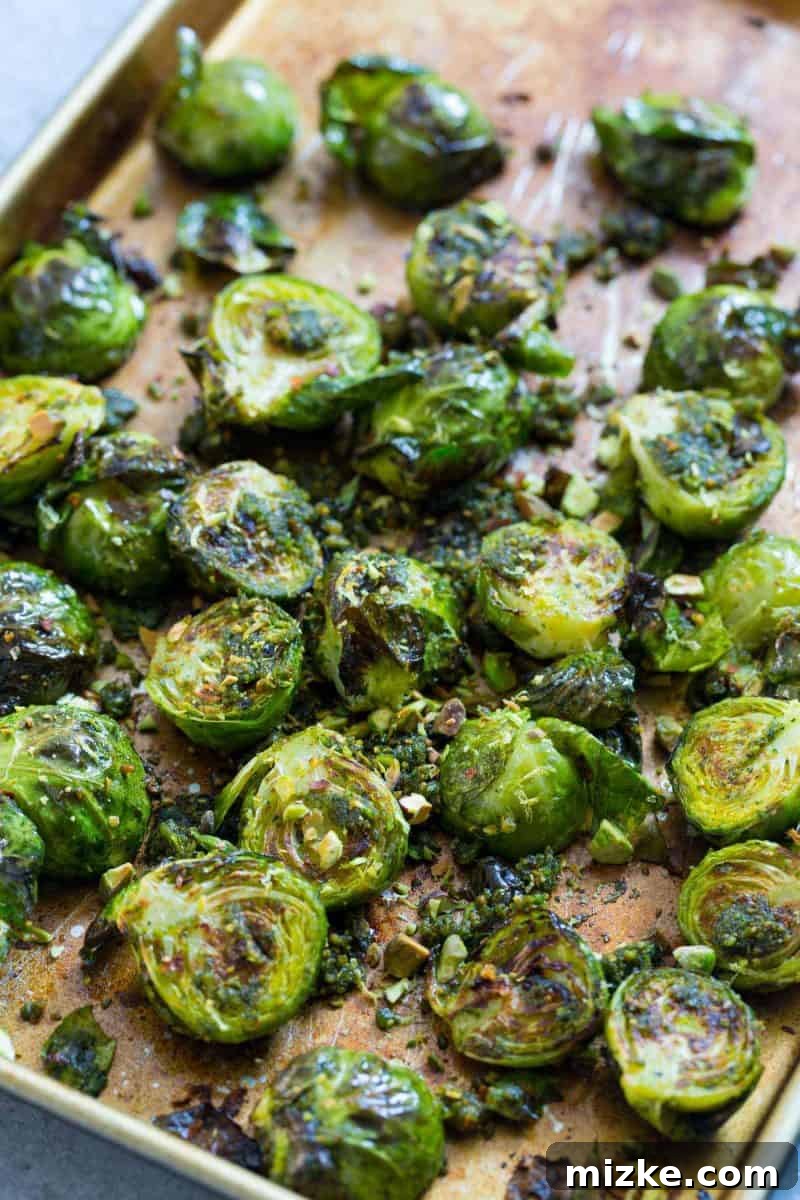 Crispy roasted brussels sprouts generously coated in vibrant pistachio pesto, promising to delight any palate.
