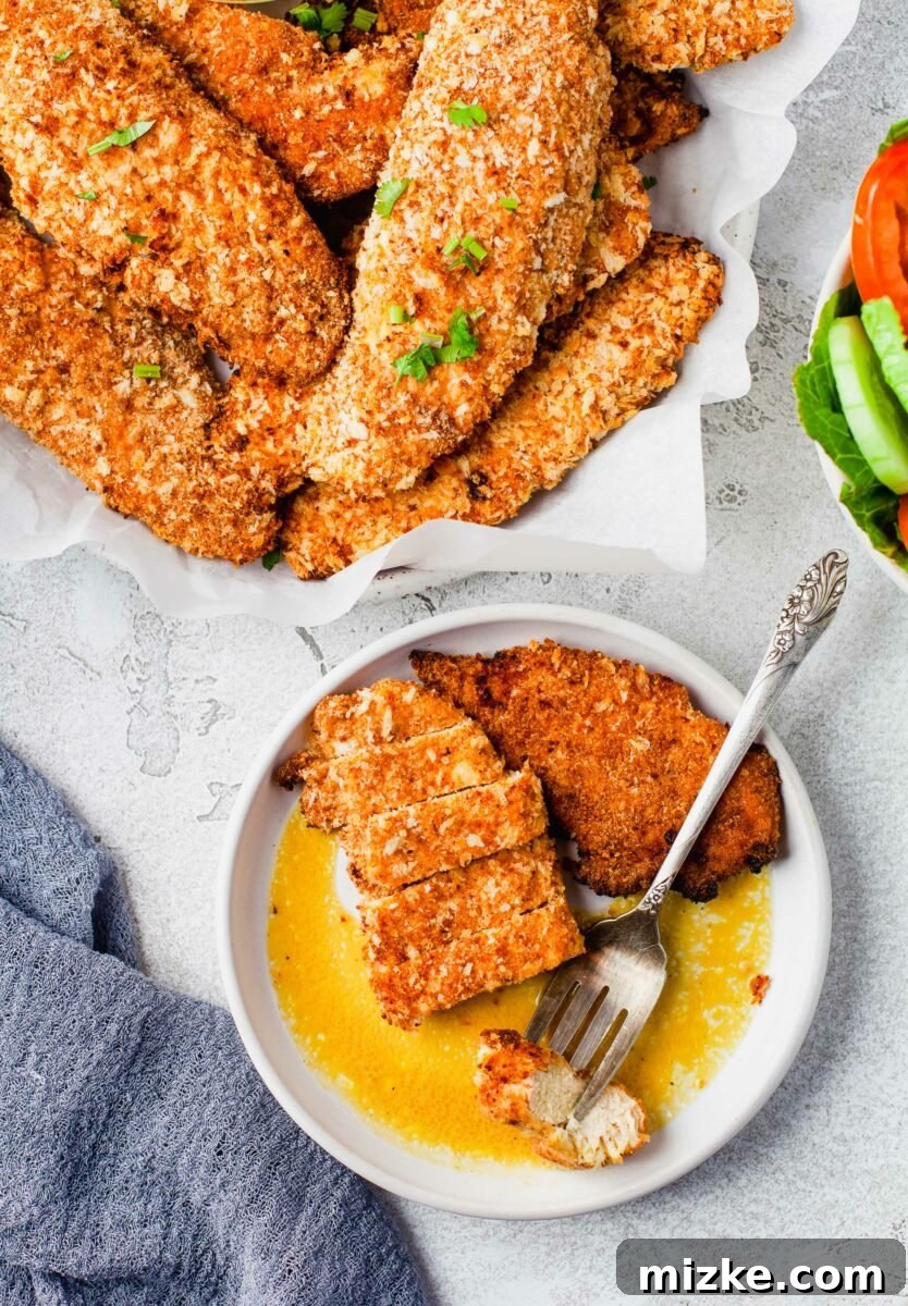 Golden Oven-Baked Chicken Tenders 5 A chicken tender is sliced into several pieces on a plate next to a whole tender.
