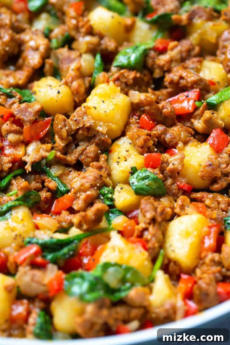 A serving of the chicken chorizo cauliflower gnocchi skillet in a bowl, garnished with fresh herbs.