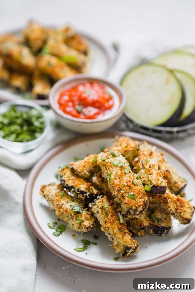 A batch of freshly baked Eggplant Parmesan Fries cooling on a wire rack after being removed from the oven.