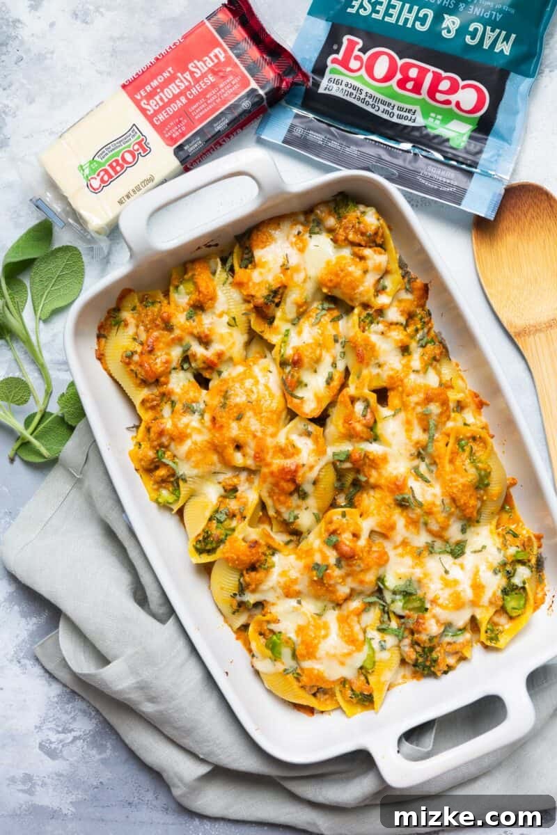 Close-up of savory pumpkin stuffed shells featuring a creamy, cheesy sauce, spicy sausage, and broccolini, highlighting the rich textures and colors.