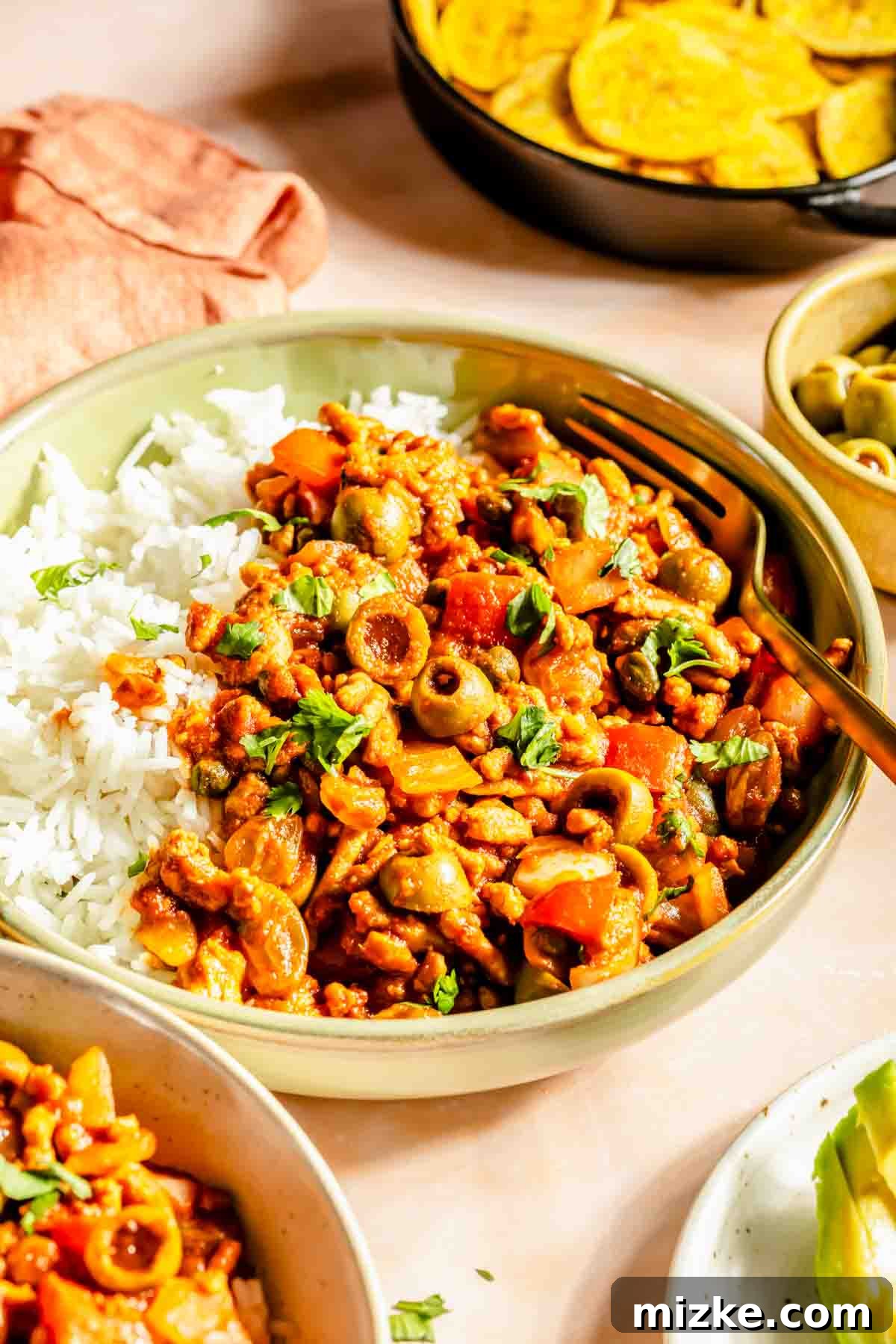 Savory Turkey Picadillo 4 Close-up of turkey picadillo on a bed of white rice in a green bowl, showing the texture and colors of the dish