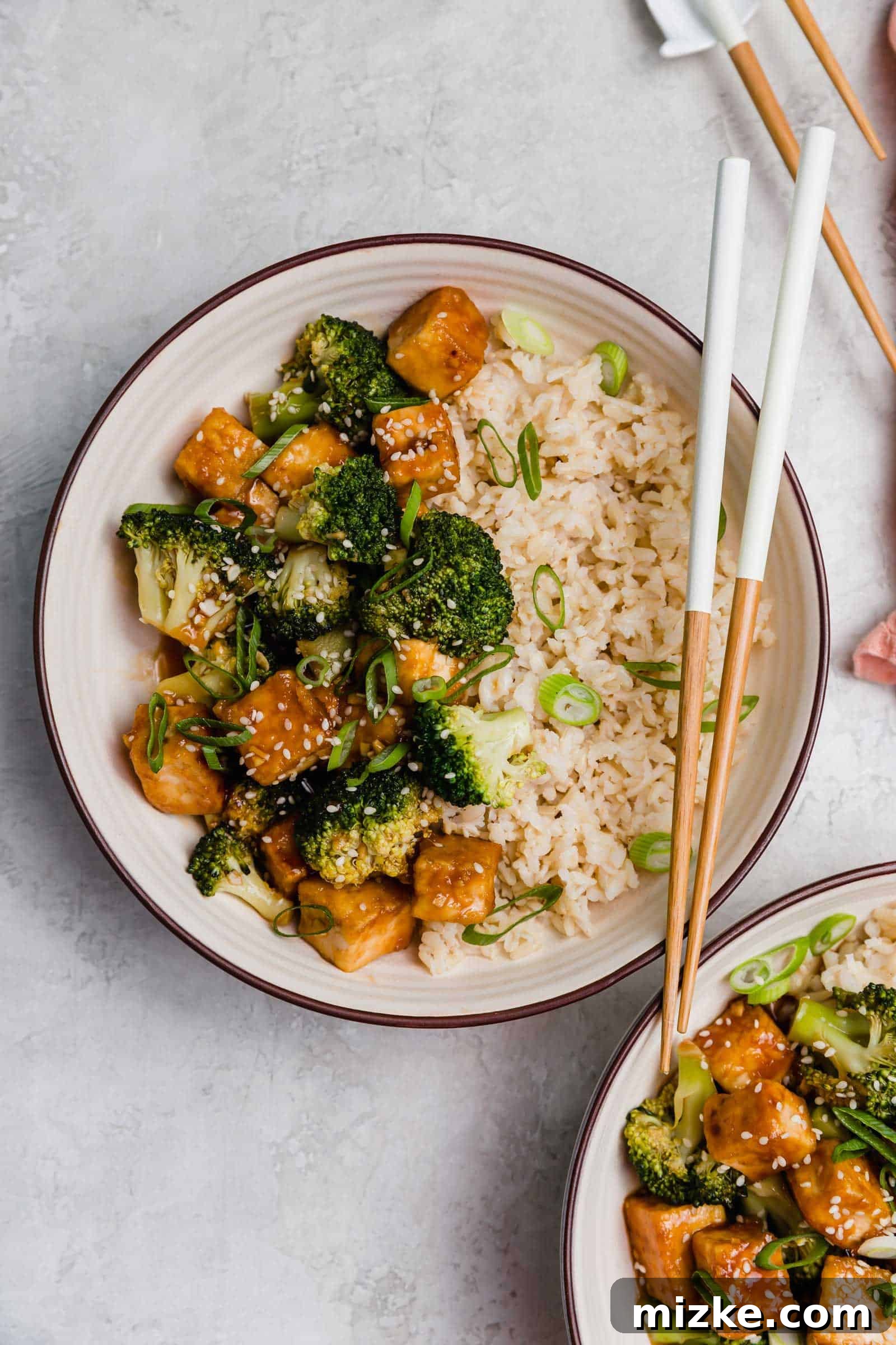 Satisfy your craving for Asian take-out with these teriyaki tofu and broccoli bowls, an easy plant-based dinner for any night of the week! Overhead view of a teriyaki tofu and broccoli bowl with a set of chopsticks.
