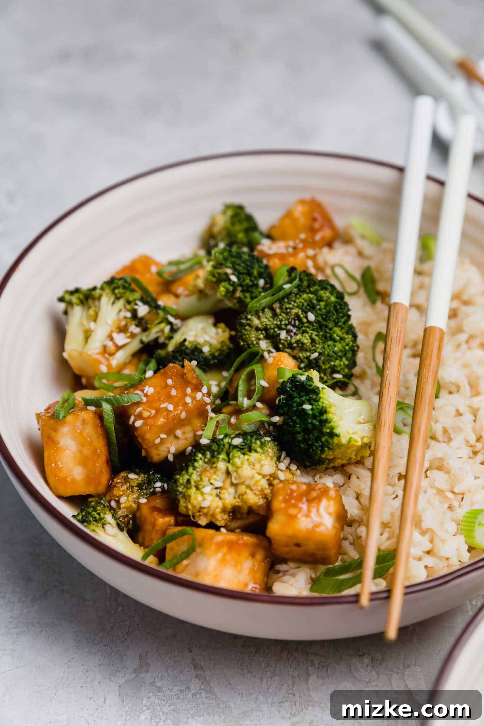 Satisfy your craving for Asian take-out with these teriyaki tofu and broccoli bowls, an easy plant-based dinner for any night of the week! Close up of a teriyaki tofu and broccoli bowl with a set of chopsticks.