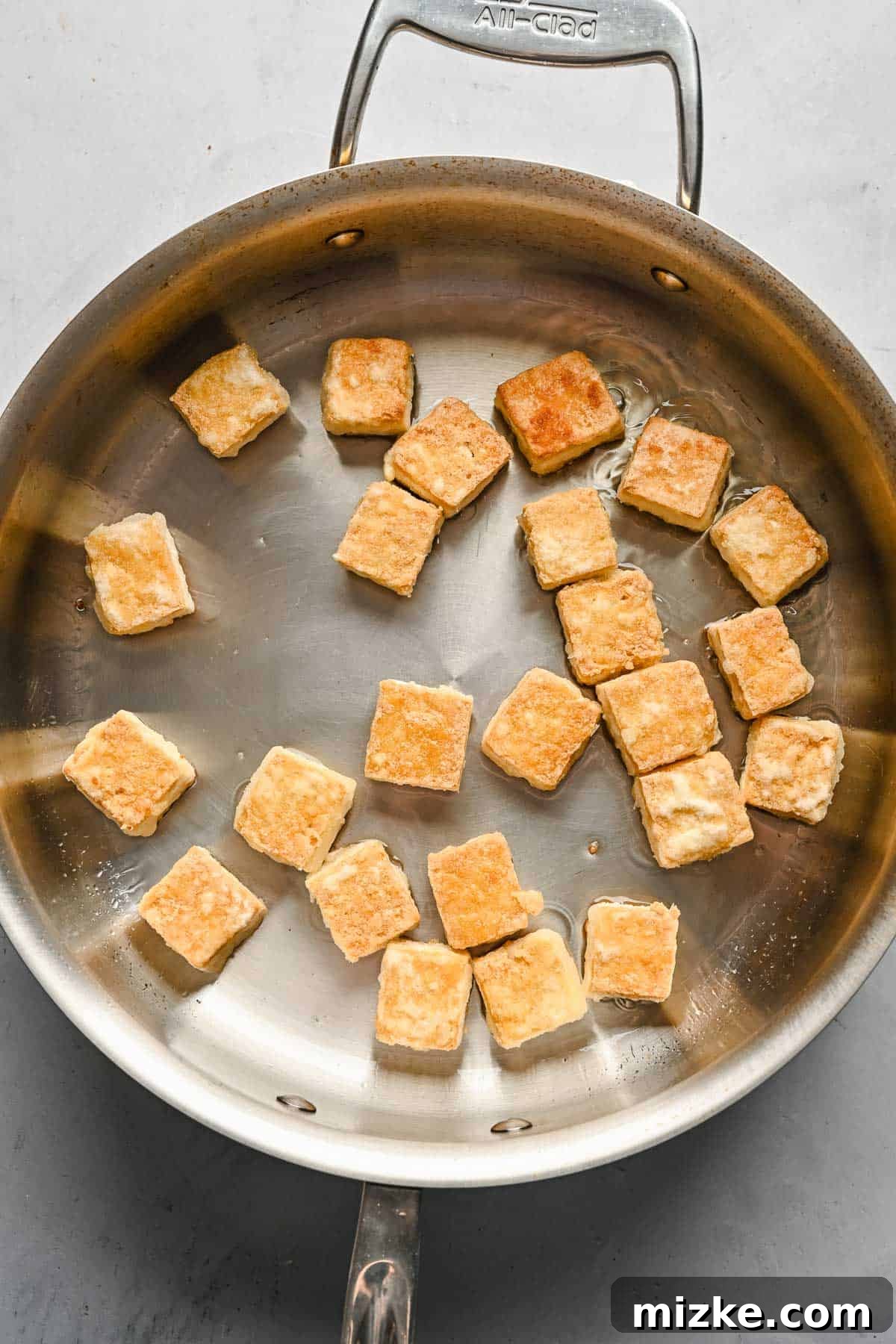 Satisfy your craving for Asian take-out with these teriyaki tofu and broccoli bowls, an easy plant-based dinner for any night of the week! Browned cubed tofu in a metal skillet.
