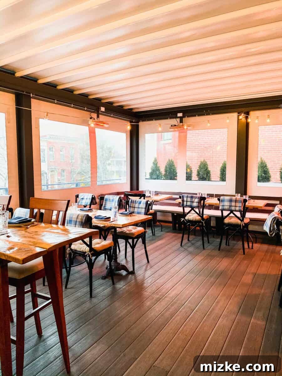 Nina May's DC Rendezvous 4 The enclosed and heated rooftop dining area at Nina May, featuring comfortable chairs and subtle lighting for a cozy evening