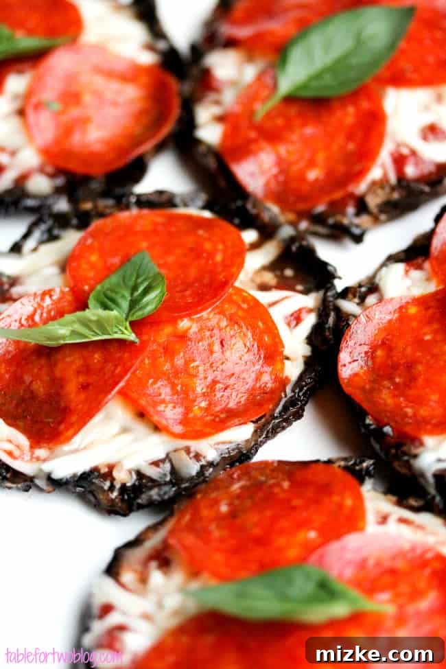 Mushroom Pizza Bites 2 Two grilled portobello mushroom pizza caps on a white plate, one with pepperoni and the other with melted cheese, garnished with fresh basil