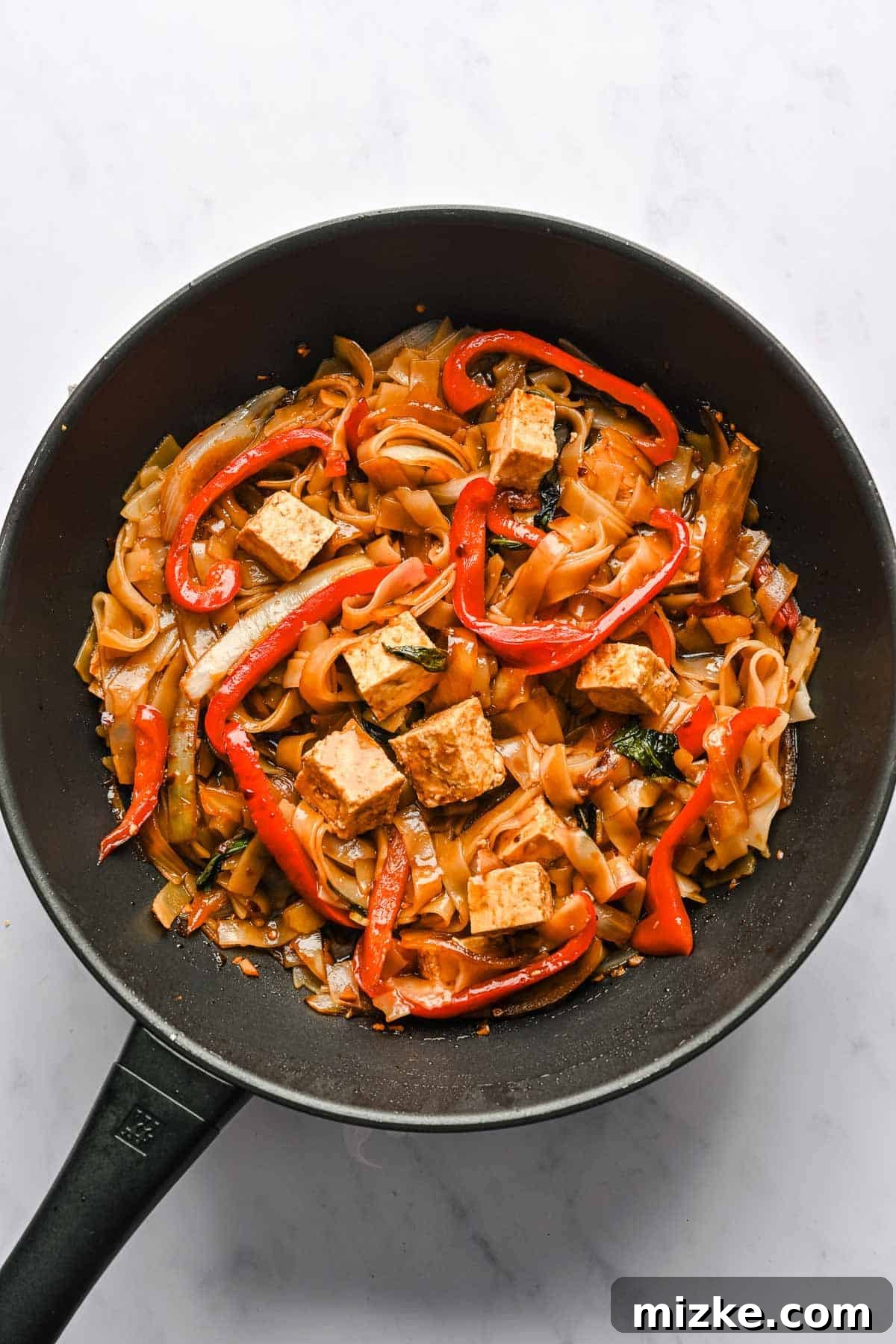 This recipe for drunken noodles with tofu is full of flavor and easy enough for a weeknight. Make your favorite Thai dish right at home! Drunken noodles in a wok.