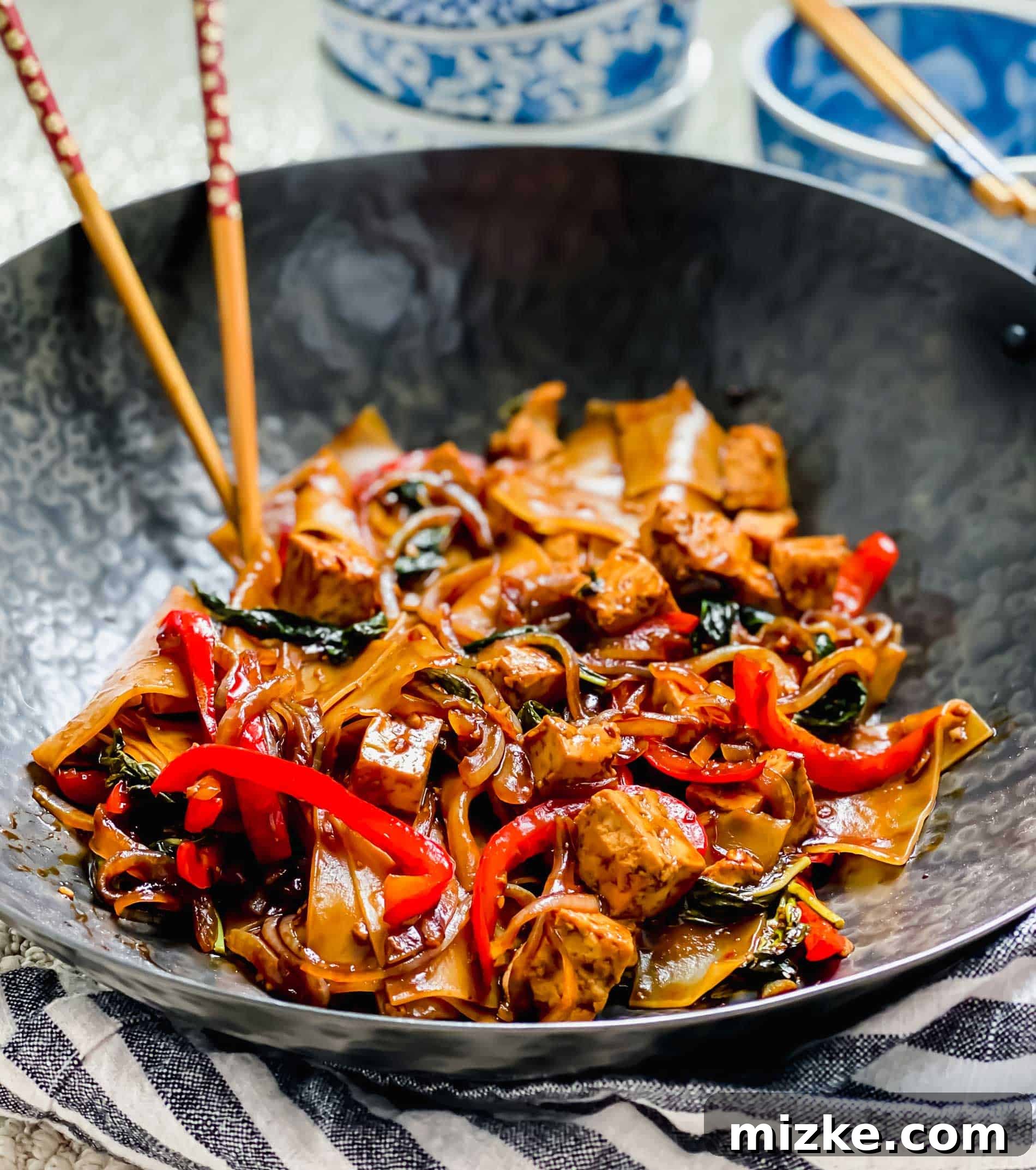This recipe for drunken noodles with tofu is full of flavor and easy enough for a weeknight. Make your favorite Thai dish right at home! Drunken noodles with tofu in wok with chopsticks.
