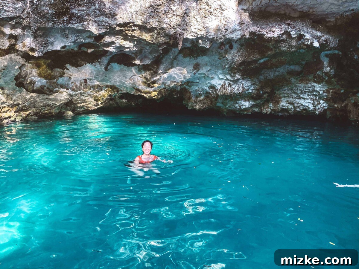 Tulum Vibes with My Tribe 13 A group of people enjoying a refreshing swim in a cenote, with lush greenery overhead.
