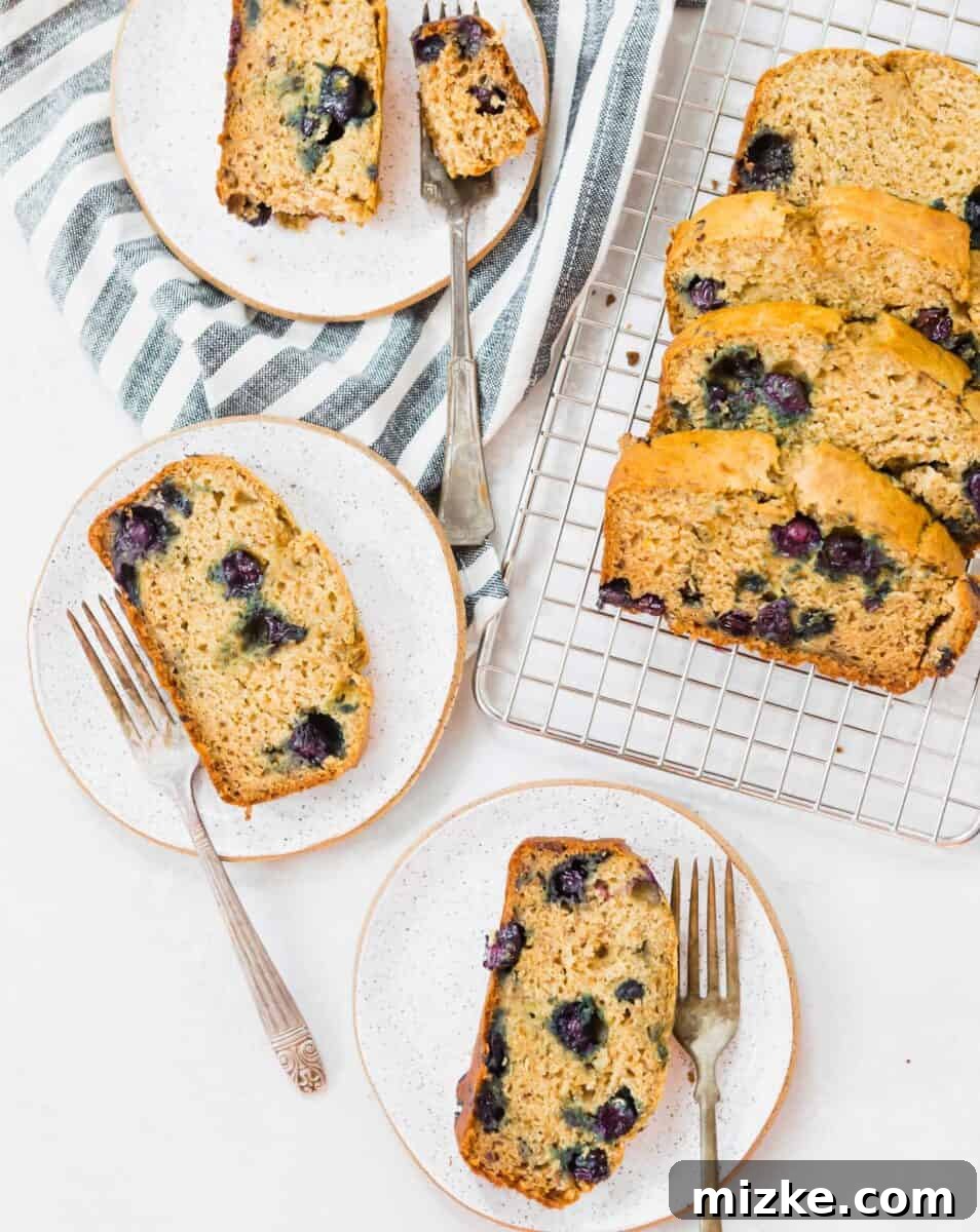 Blueberry Burst Banana Loaf 2 Freshly baked blueberry banana bread loaf with a slice cut out, showcasing its moist texture and vibrant blueberries.