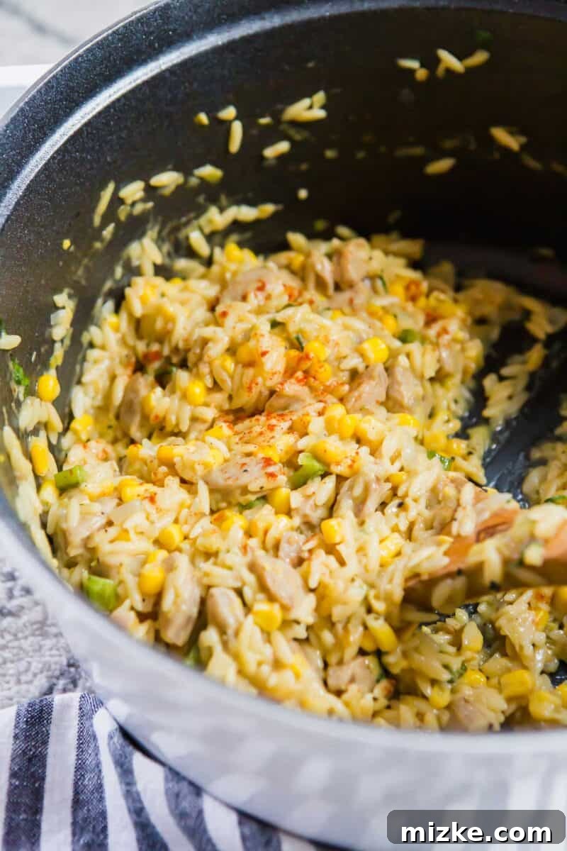 A serving of creamy poblano corn orzo in a bowl, garnished with fresh basil leaves.