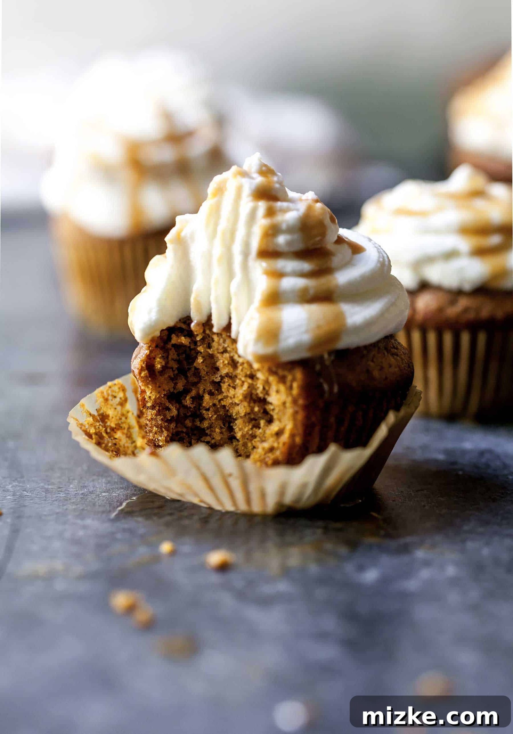 Cozy Pumpkin Spice Latte Cupcakes 5 Closeup shot of a pumpkin spice latte cupcake unwrapped, with a bite taken out, showing the moist interior.