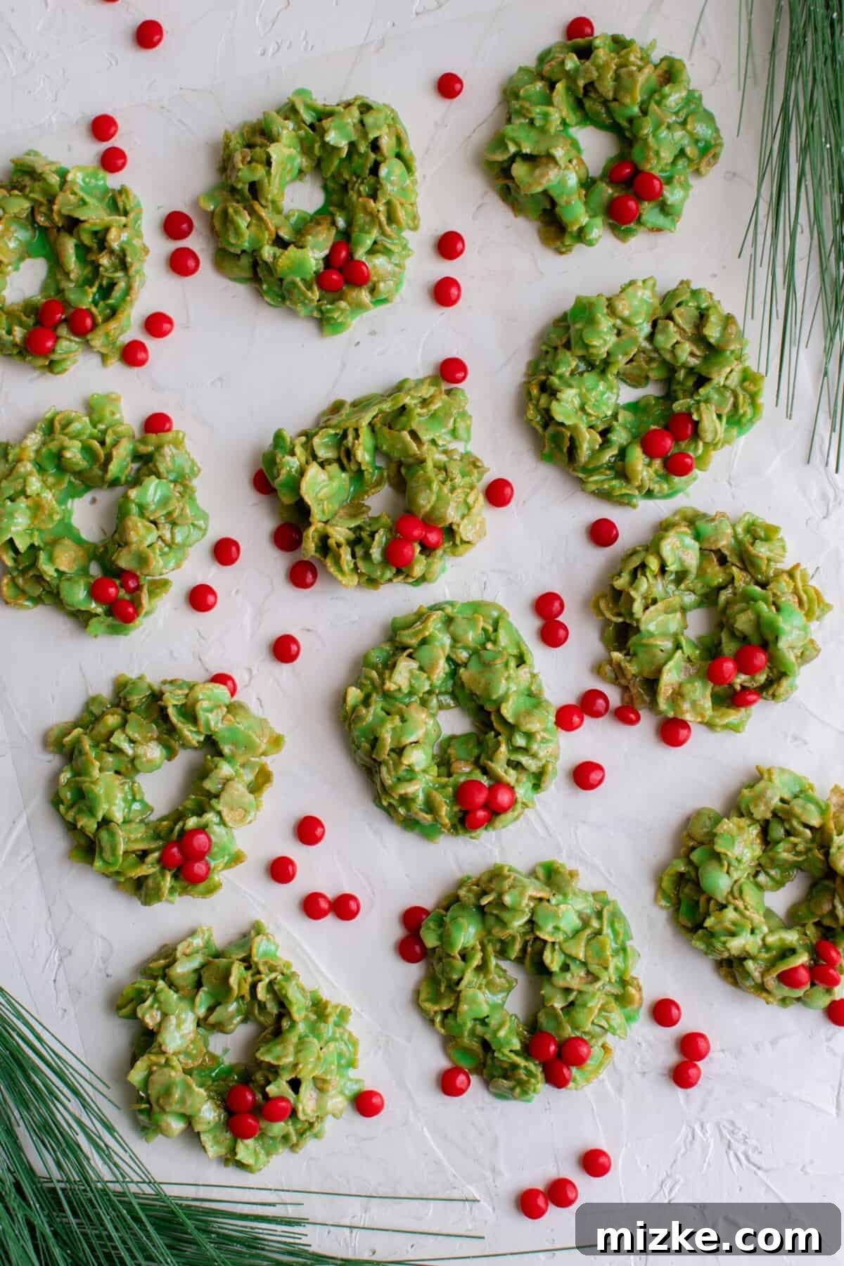 Crunchy Wreath Delights 7 A beautifully arranged batch of green cornflake wreaths, with red hots scattered artfully nearby, ready for festive serving.