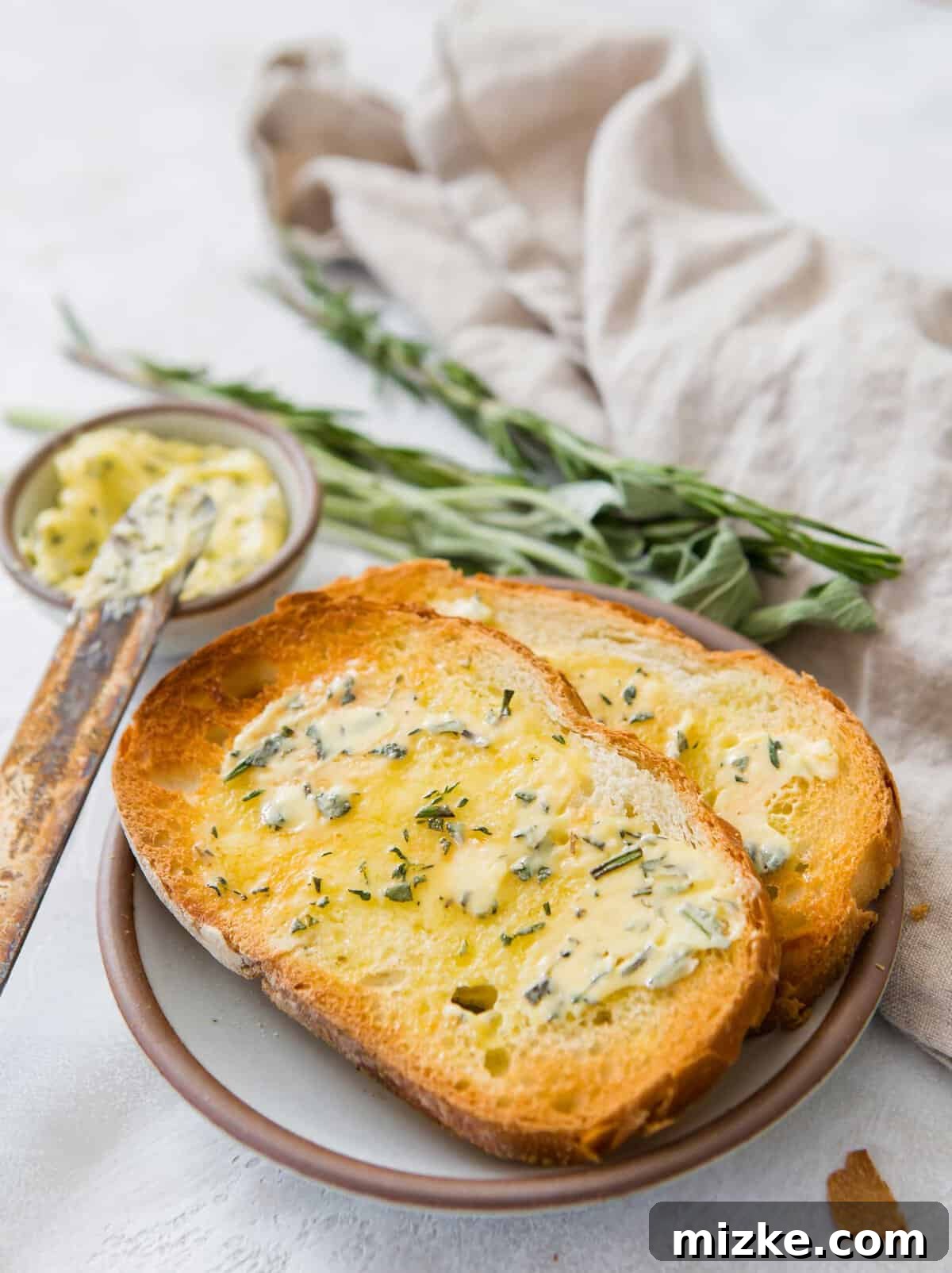 Gourmet Herb Butter 4 Two pieces of toast topped with melted compound butter on a plate