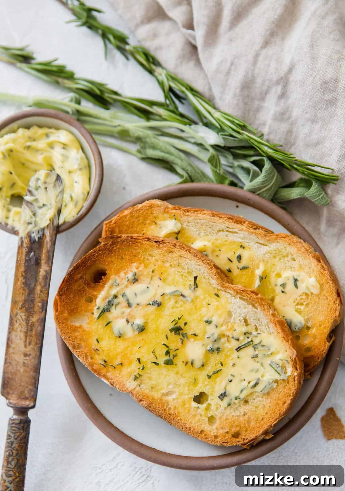 Gourmet Herb Butter 7 Overhead view of two pieces of toast on plate, each topped with herbed compound butter