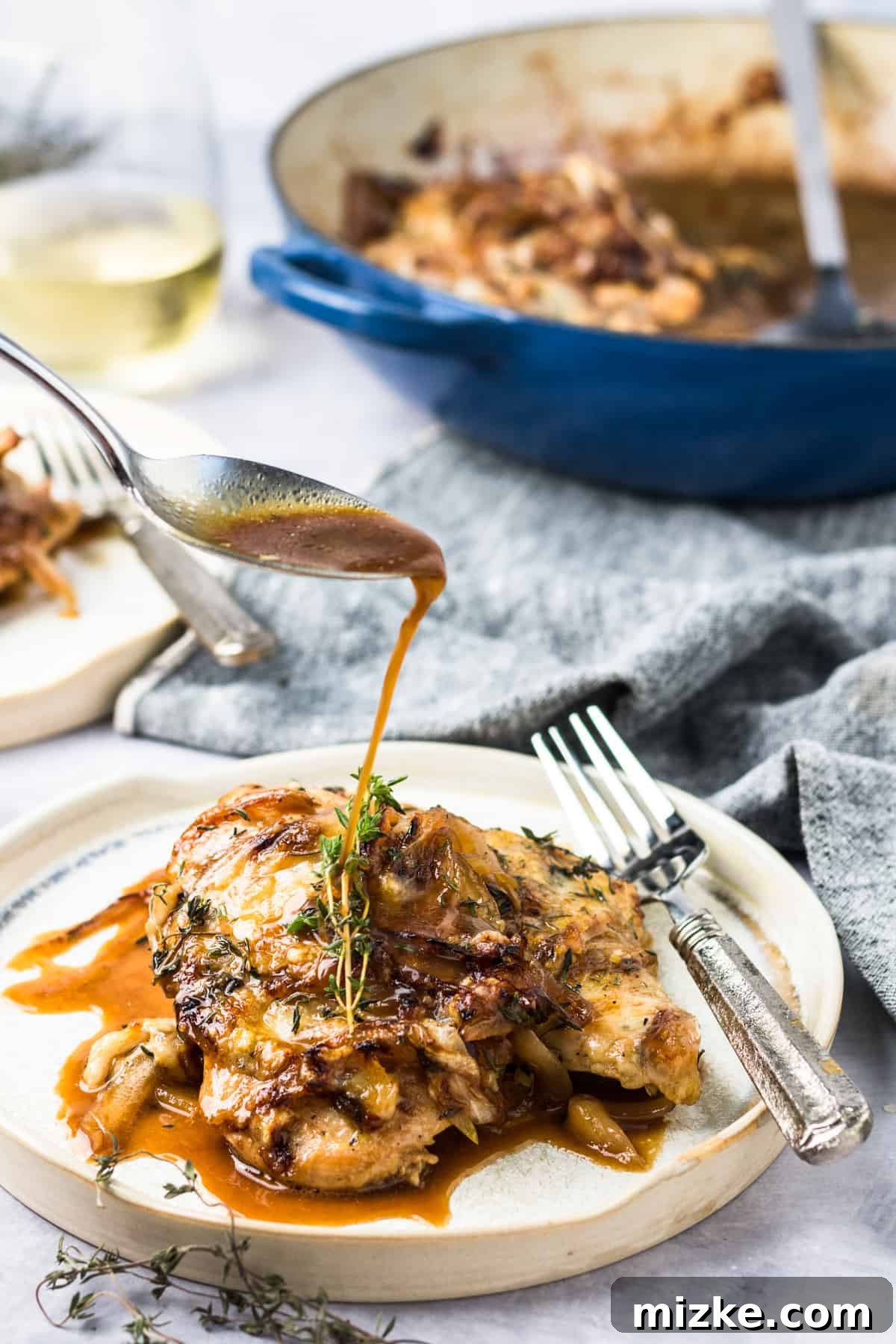 French Onion Smothered Chicken 3 a spoon drizzles au jus from french onion chicken onto a plated piece of chicken