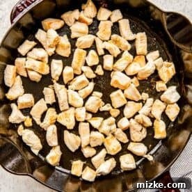 browned chicken pieces in a cast iron skillet