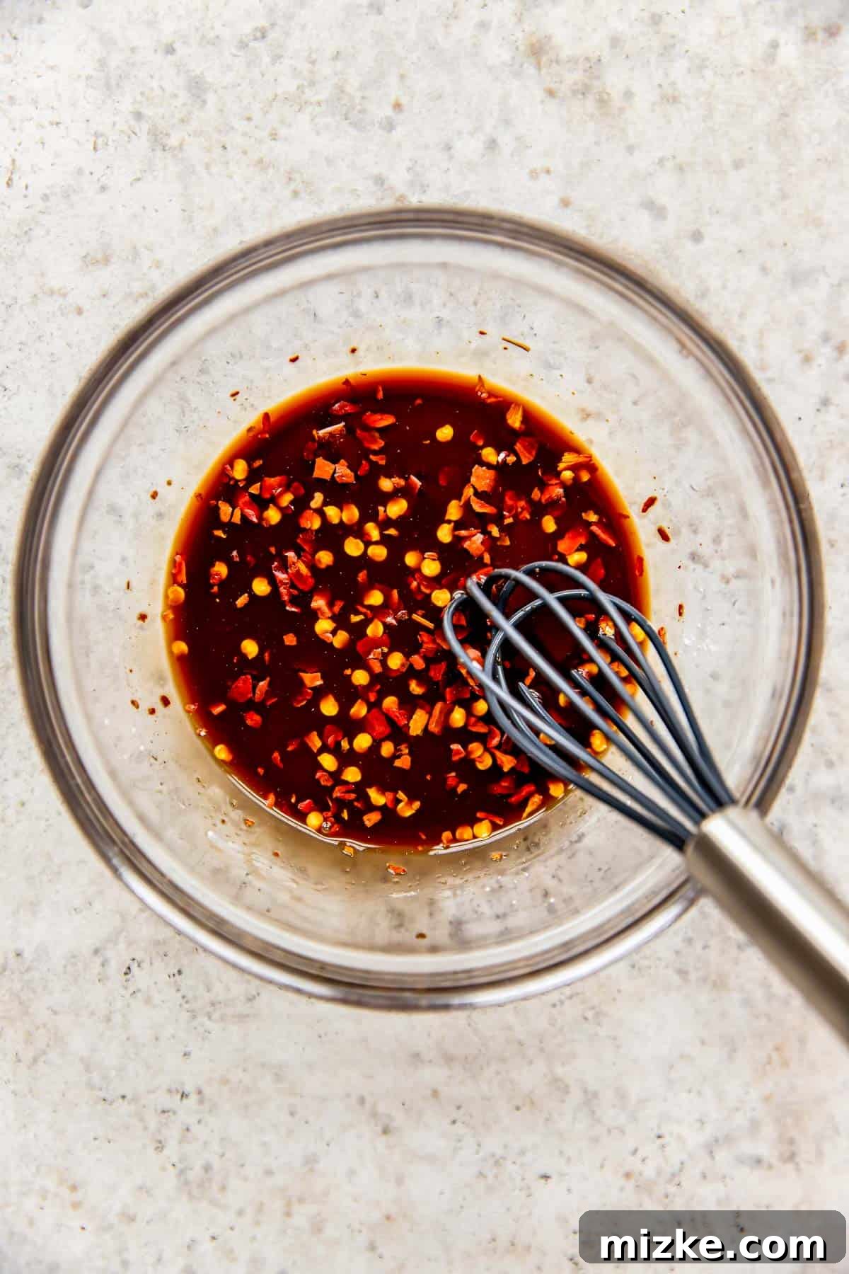Spicy Szechuan Peanut Chicken 4 Kung Pao Chicken sauce ingredients being whisked together in a clear bowl with a metal whisk.