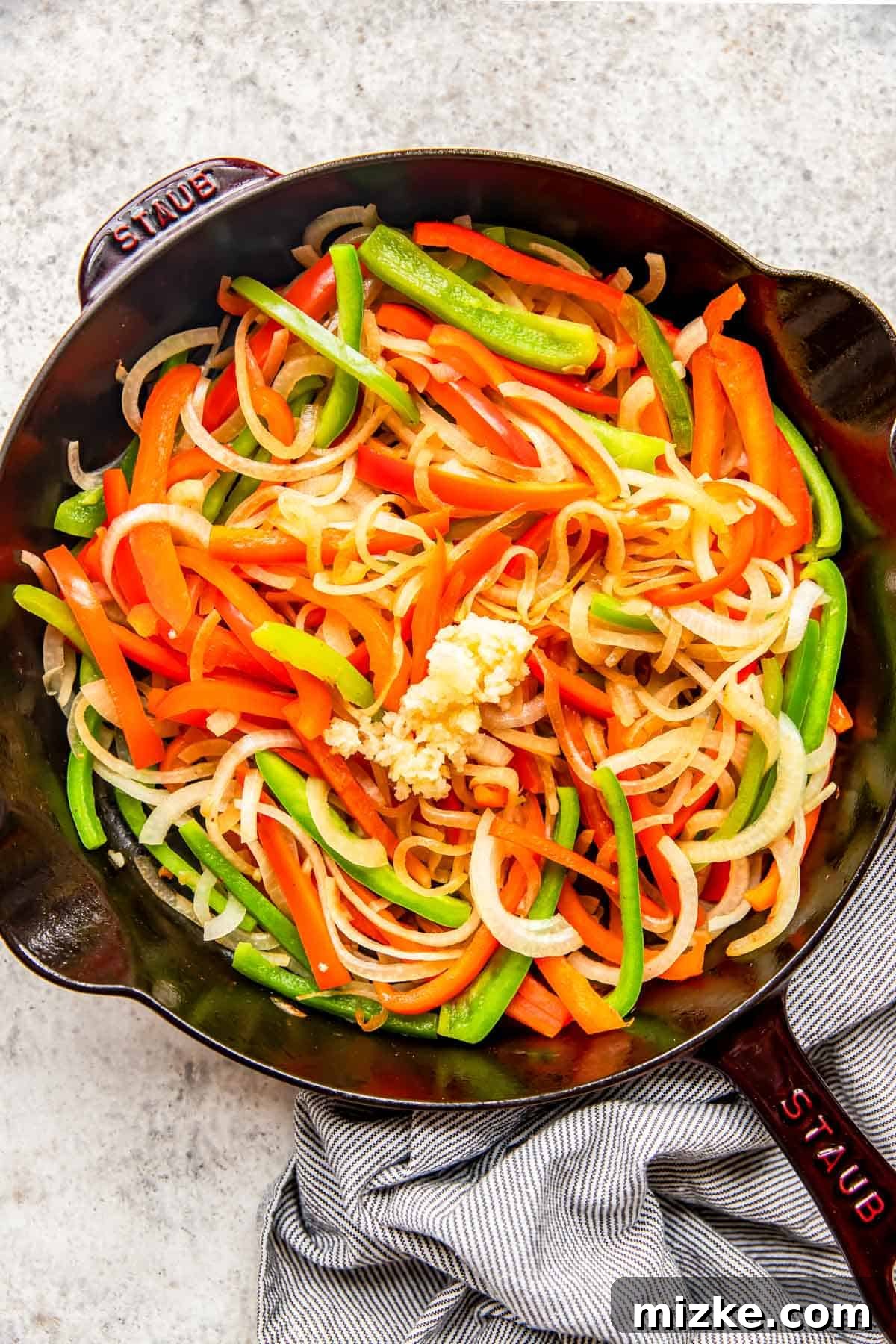 Spicy Szechuan Peanut Chicken 6 Sautéing a colorful mix of bell peppers, onions, and garlic in a cast iron skillet.