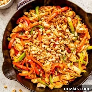 finished kung pao chicken in a cast iron skillet topped with chopped peanuts