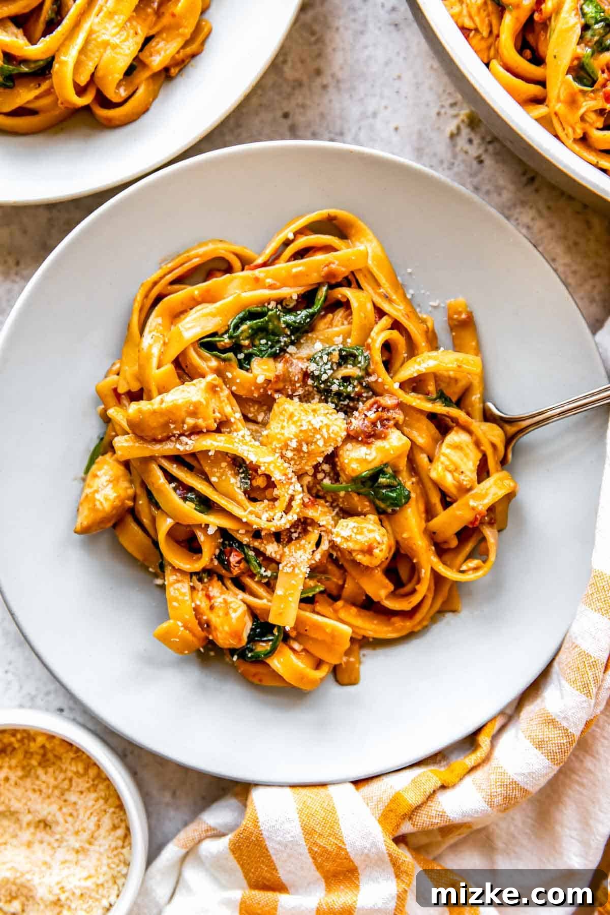 Sun-Kissed Skillet Chicken Pasta 13 A beautifully presented bowl of sun-dried tomato chicken pasta, generously topped with freshly grated Parmesan cheese, ready to be enjoyed
