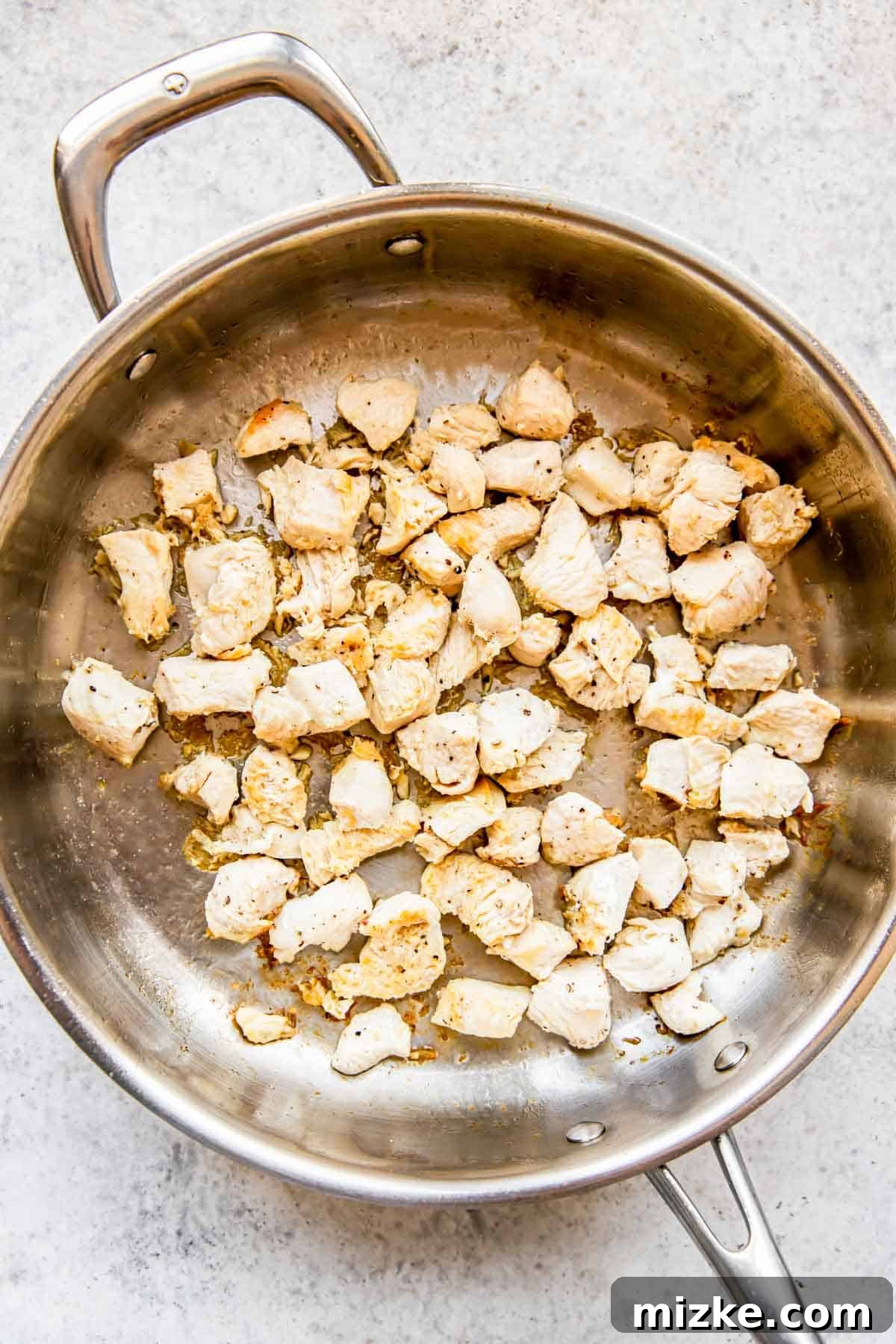 Sun-Kissed Skillet Chicken Pasta 5 Cubed chicken browning beautifully in a stainless steel skillet over medium-high heat