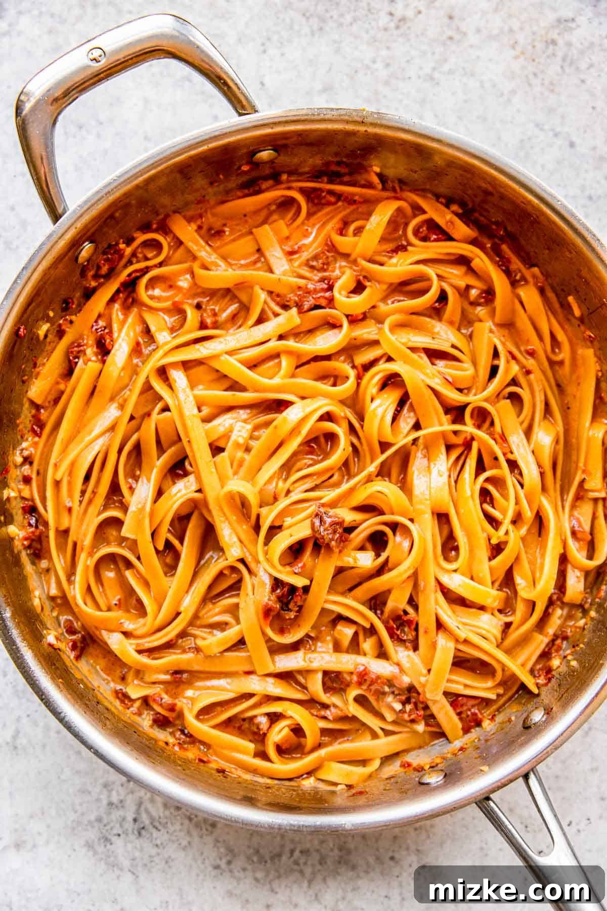 Sun-Kissed Skillet Chicken Pasta 10 Perfectly cooked linguine pasta, glistening in a thick, creamy sauce within the stainless steel skillet