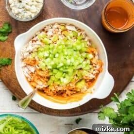 buffalo chicken mixture with fresh celery and cilantro in a white bowl, ready for crunchwrap assembly