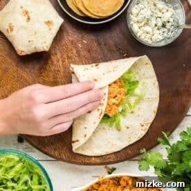expertly folding the large flour tortilla towards the center to seal the buffalo chicken crunchwrap