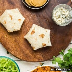 the buffalo chicken crunchwrap is seam-side down on the wooden cutting board, ready for pan-frying