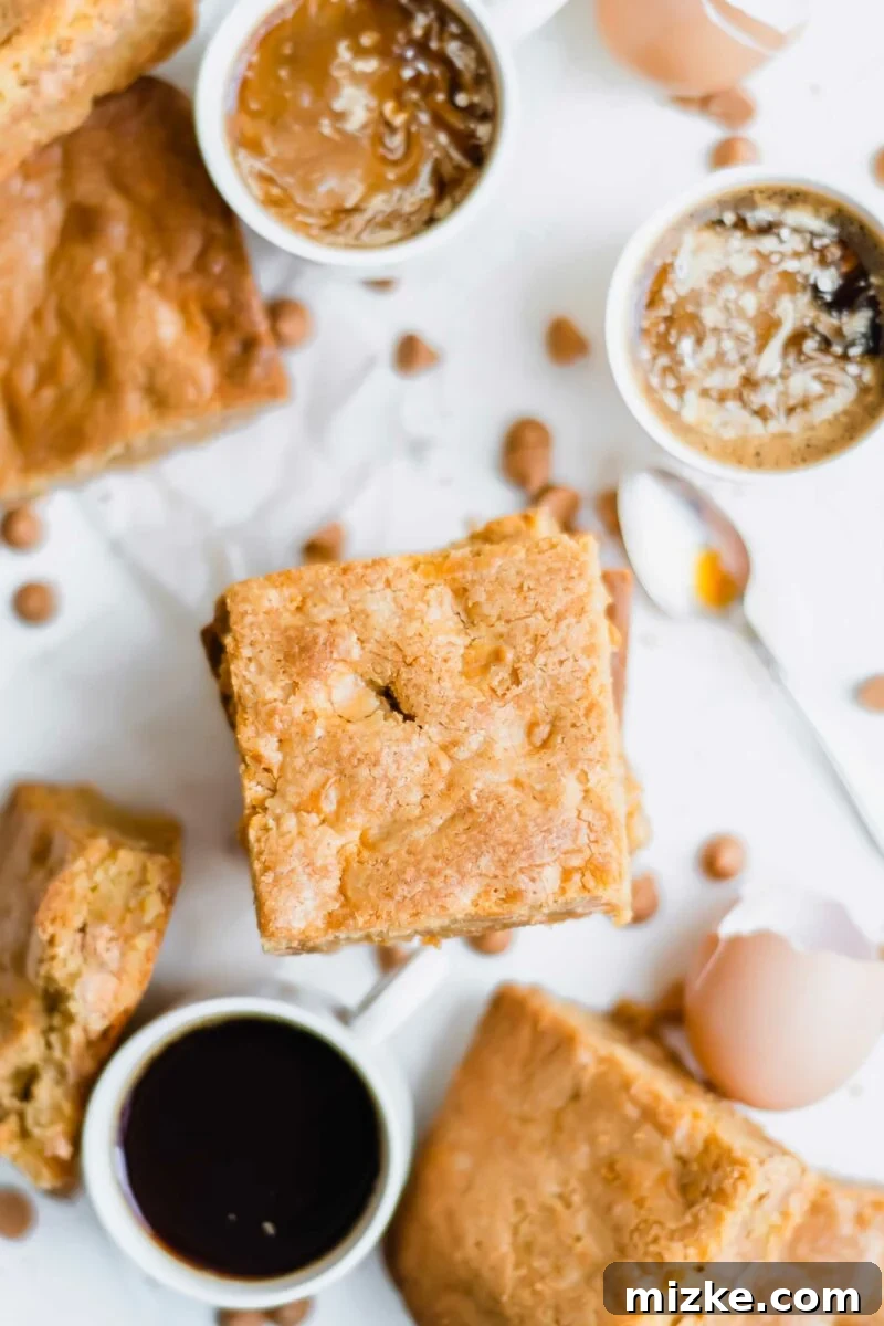 Golden Chewy Blondies 5 Several cups of coffee are artfully arranged next to a small plate of butterscotch blondies, suggesting a perfect pairing for a cozy break.