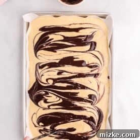 chocolate sauce being swirled into pancake batter with a butter knife