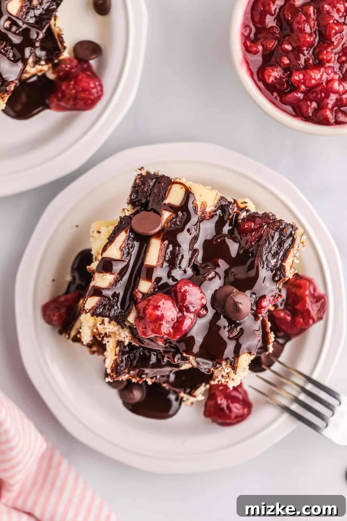 Chocolate Cherry Pancake Bake 3 Squares of chocolate cherry pancakes stacked beautifully, topped with generous chocolate syrup and fresh tart cherries