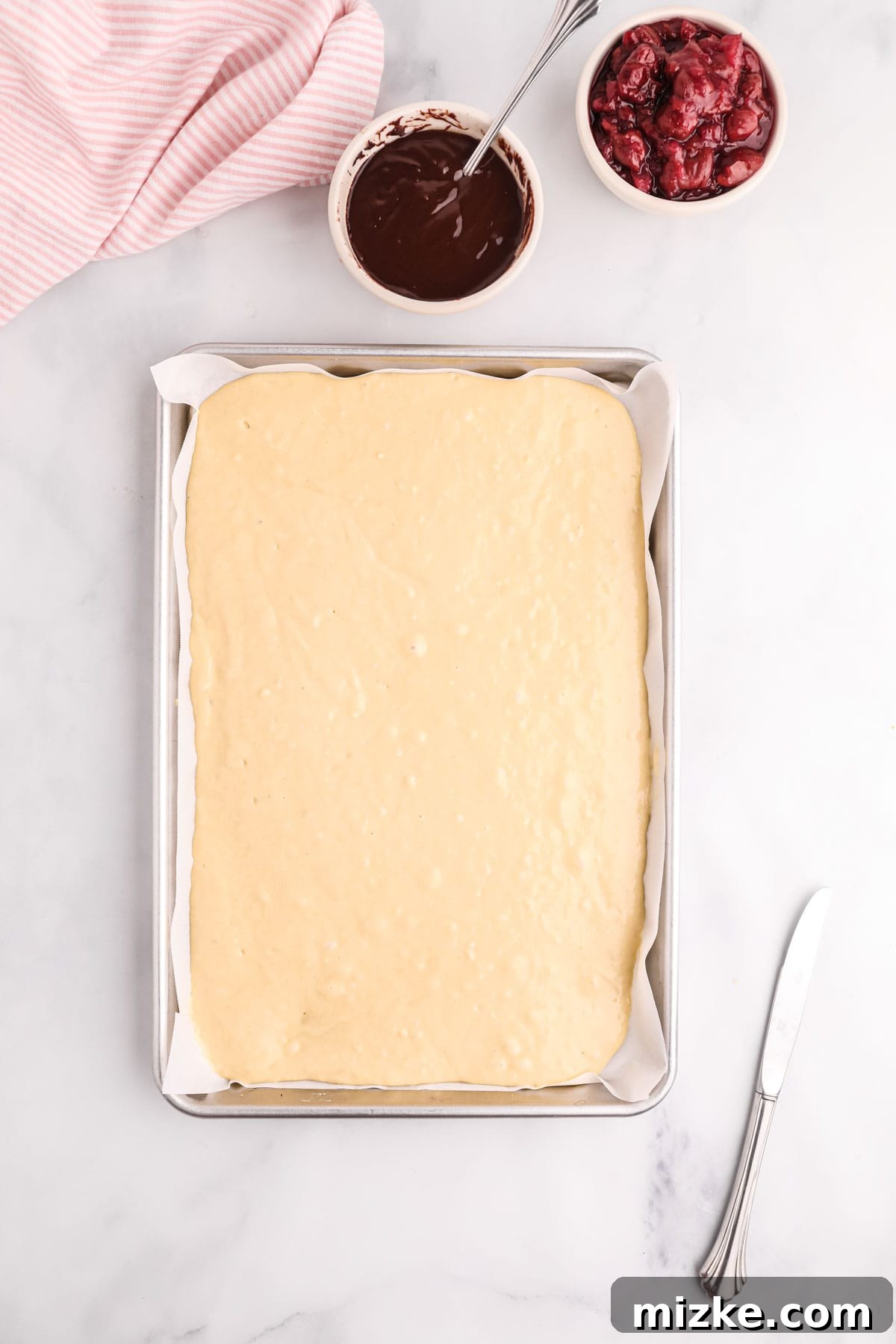 Chocolate Cherry Pancake Bake 5 Pancake batter poured into a parchment paper-lined metal sheet pan, ready for the oven