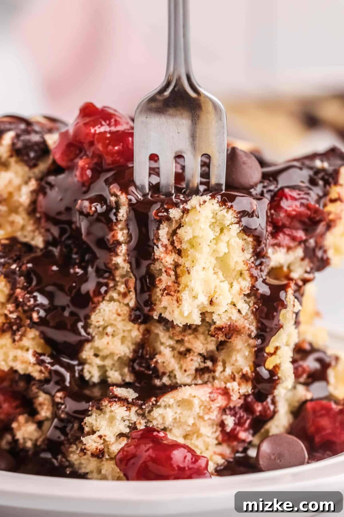 Chocolate Cherry Pancake Bake 8 A fork piercing a stack of chocolate cherry sheet pan pancakes, highlighting their fluffy texture