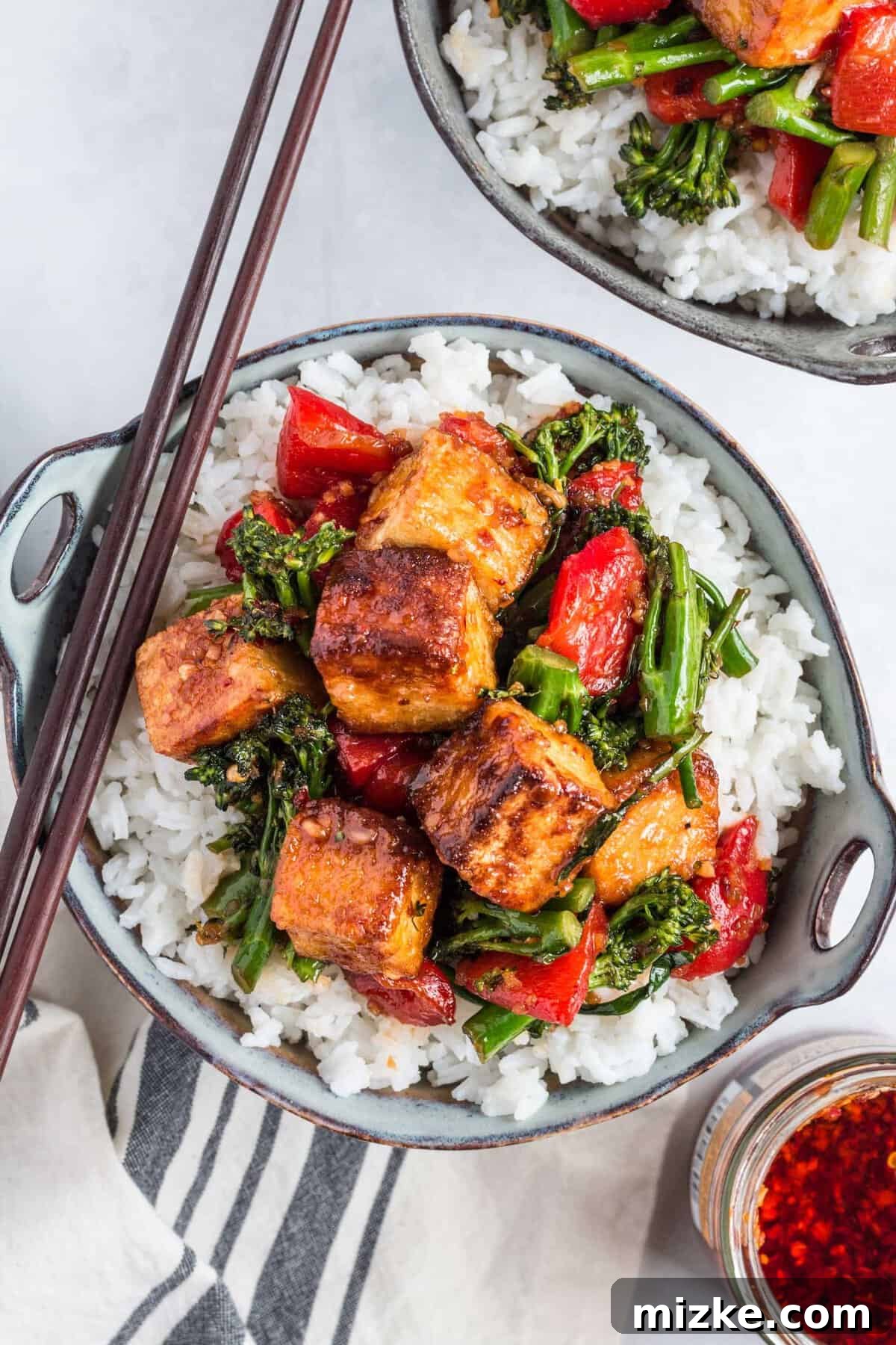 Crispy Tofu Stir-Fry 12 Two perfectly portioned bowls of white rice topped with spicy chili tofu stir fry are beautifully arranged on a clean white surface, garnished and ready to be enjoyed as a wholesome, flavorful meal.