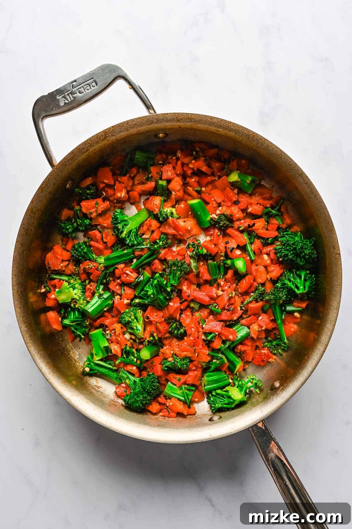 Crispy Tofu Stir-Fry 9 Bright red diced roasted peppers and fresh green broccolini are stir-fried to perfection in a large metal skillet, releasing their vibrant aromas.