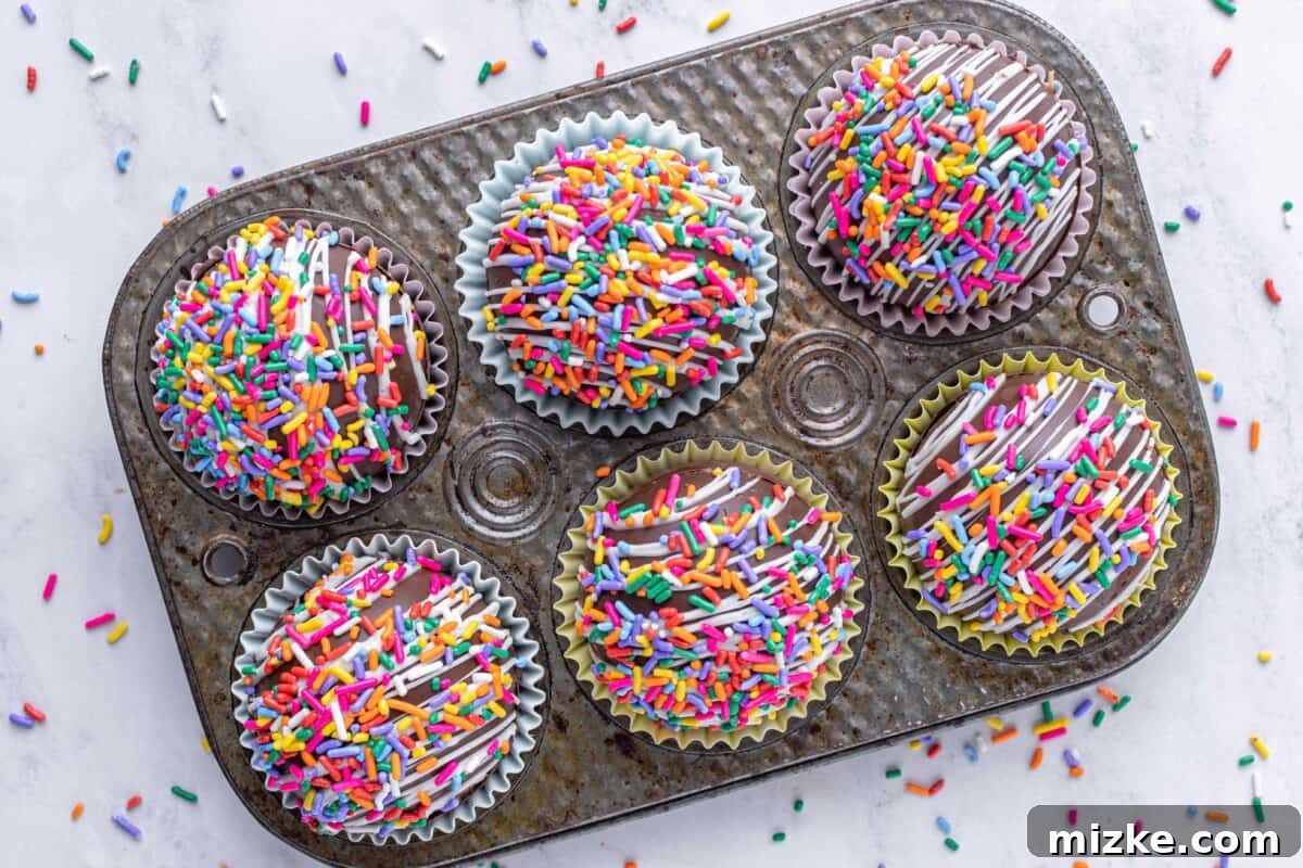 Vibrant Chocolate Dissolves 3 Six funfetti cocoa bombs are placed in a metal tray, showcasing their vibrant colors and perfect spherical shape.