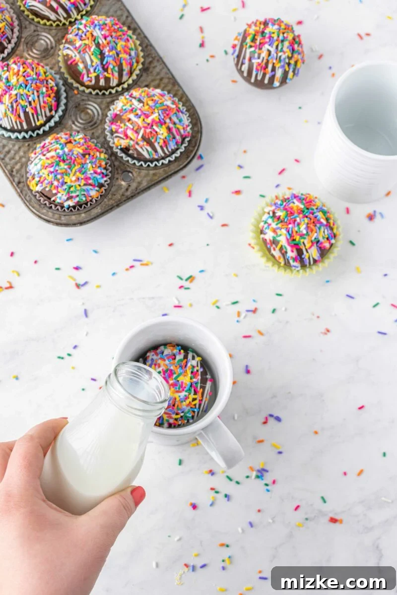 Vibrant Chocolate Dissolves 6 Milk from a jaw is being poured onto a funfetti cocoa bomb in a white mug, initiating the magical melting process.