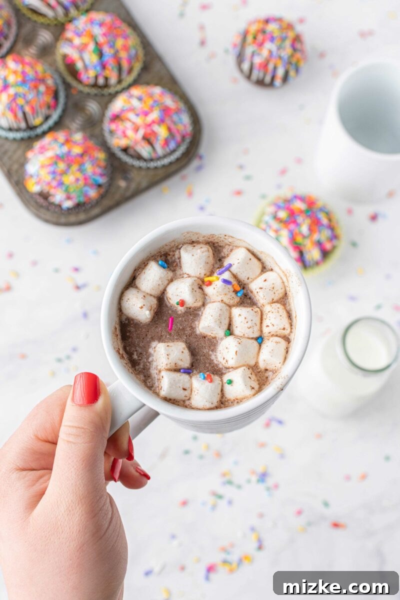 Vibrant Chocolate Dissolves 7 Marshmallows and sprinkles in a white mug are floating on top of hot cocoa, aftermath of a melted bomb, inviting a cozy sip.