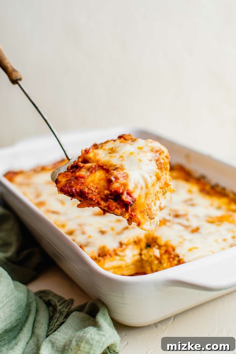 Ravioli Lasagna Bake 3 A spatula is lifting a generous piece of ravioli lasagna out of the baking dish, showing off its cheesy layers.