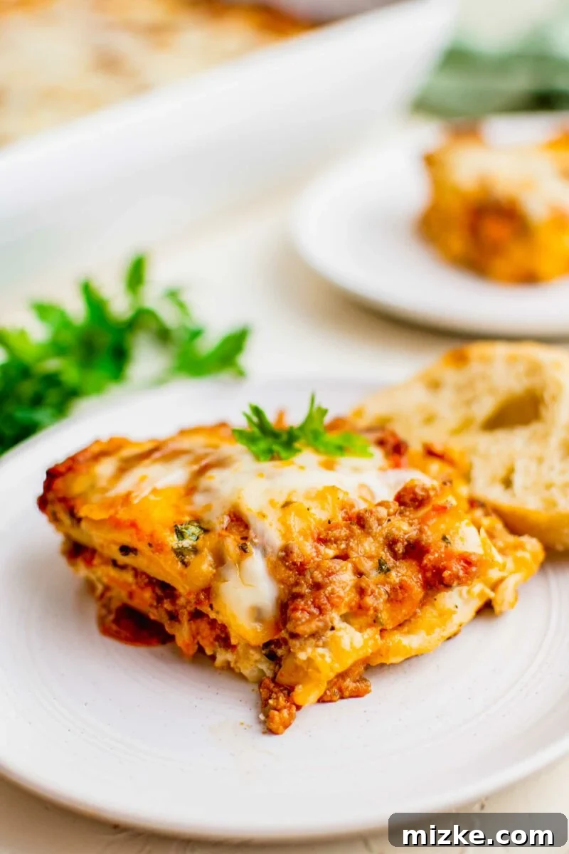 Ravioli Lasagna Bake 5 Cheesy, meaty lasagna is garnished with fresh parsley on a white plate, ready to be enjoyed.