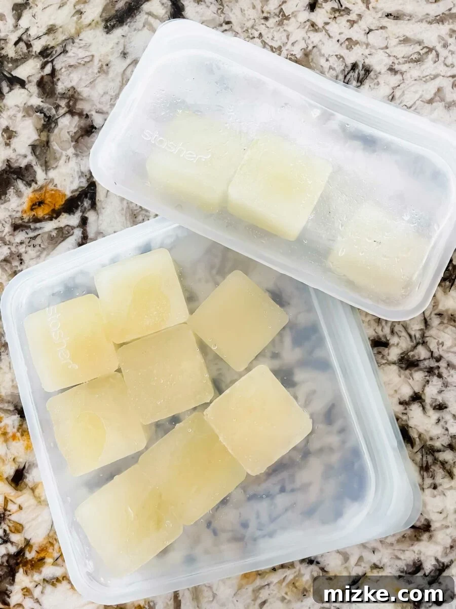 Capture Fresh Flavor: Freezing Herbs and Citrus 8 A hand transferring frozen herb cubes from a Souper Cube tray into a labeled freezer bag