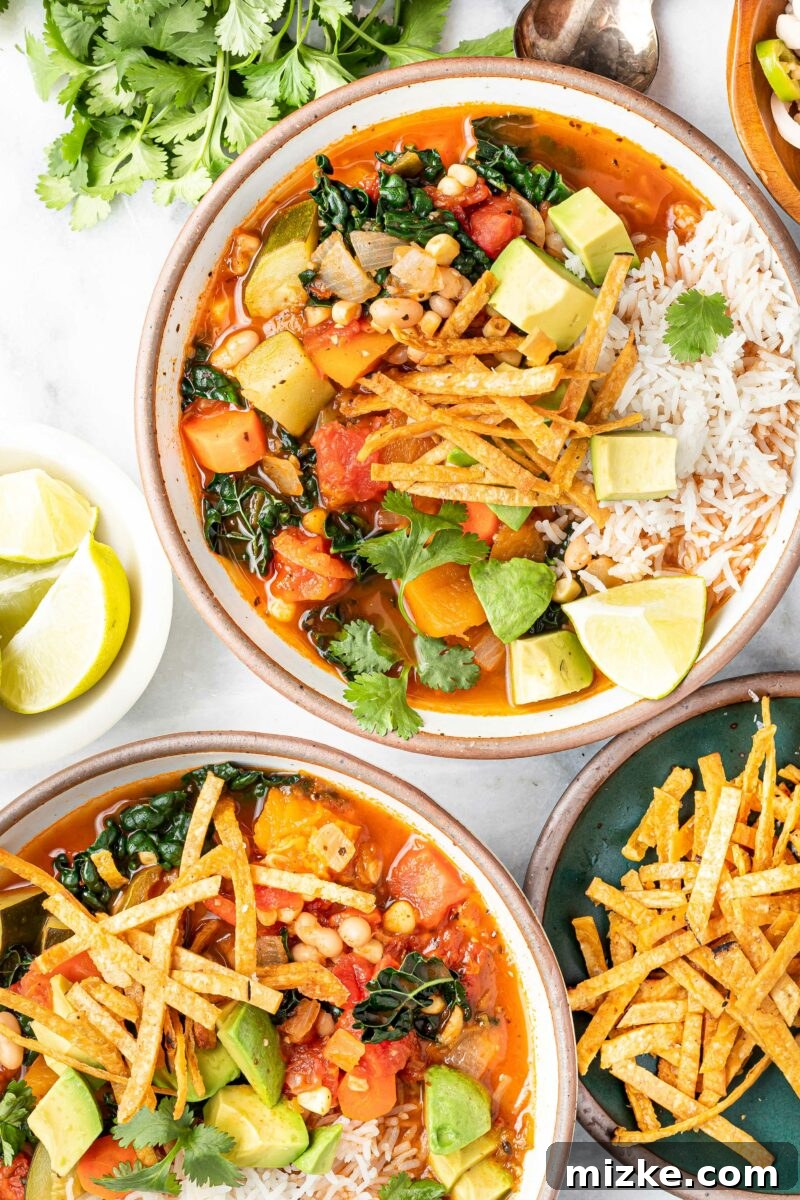 Zesty Mexican Veggie Bean Tortilla Soup 4 Two full bowls of soup are sitting next to each other with tortilla strips and lime on the side.