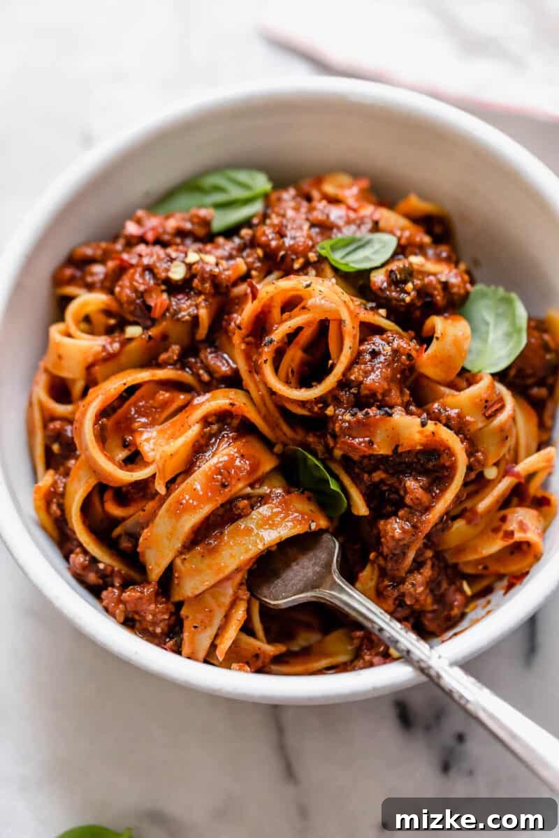 Great-Grandma's Heirloom Pasta Sauce 2 A close-up of a bubbling pot of rich Great Grandma's Pasta Sauce, showcasing its deep red color and tender ground beef, ready to be served over pasta.